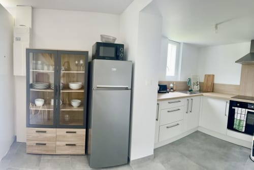 Modern kitchen with cream cabinetry, stainless steel appliances, and dining area in Le Clos 5 cottage at Le Clos De La