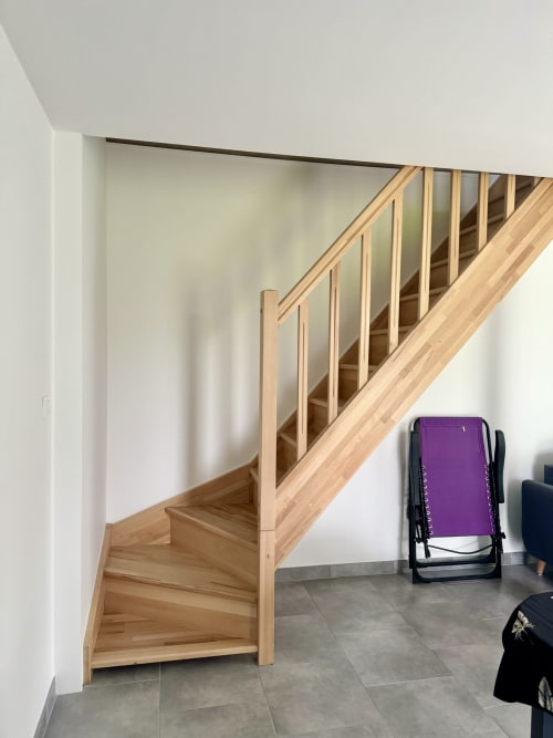 Modern wooden staircase with metal railings in Le Clos De La Vallée cottage, gray tile flooring, white walls, purple chair