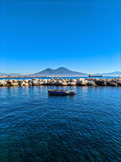 Barca da pesca ancorata nella baia di Napoli con il Vesuvio sullo sfondo, vicino all'Hotel Encanto
