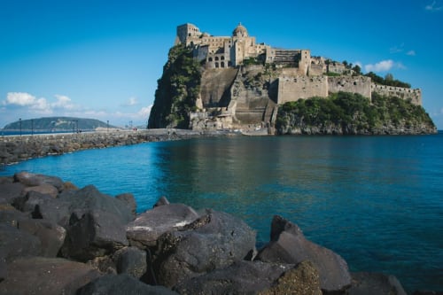 Castello Aragonese su isola rocciosa nel mare blu di Napoli, Italia con storica fortezza in pietra affacciata sulle acque costiere