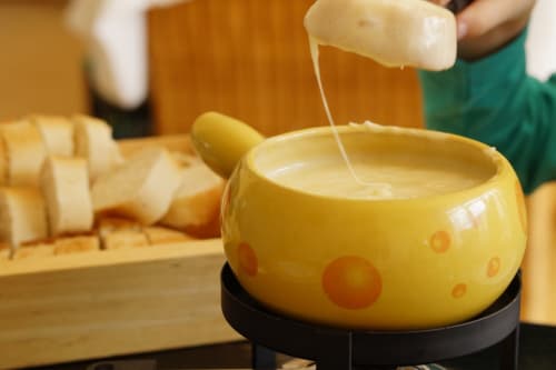 Fondue de fromage versée dans un bol jaune à pois aux Louettes à Saxon, Suisse