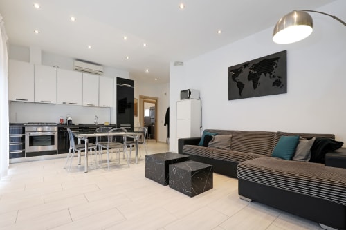 Moderno appartamento open space a Re di Roma a Roma con cucina, zona pranzo e soggiorno con divano rigato e vista sulla città