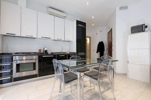 Moderna cucina e zona pranzo dell'appartamento Re di Roma a Roma con elettrodomestici in acciaio inox e vista sulla città