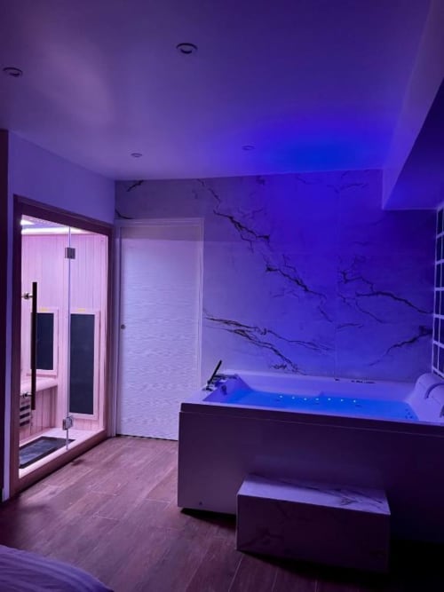 Espace Spa de l'appartement bulle évasion. Le sauna fait face au jacuzzi avec un éclairage bleu.