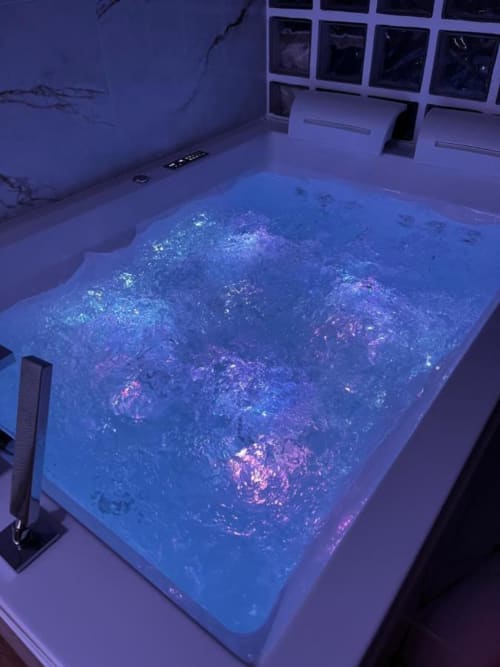 Jacuzzi en marche dans un appartement privatif. Les leds diffuent une lumière de couleur bleue.