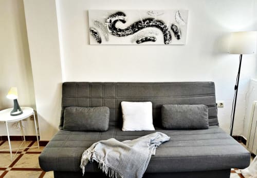 Elegante sala de estar en apartamento Mencer, Holibai Baiona con sofá gris, cojín blanco, arte mural decorativo y ambiente acogedor