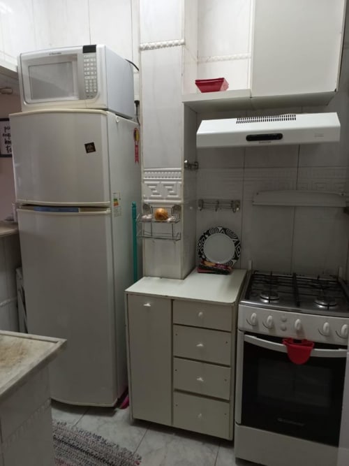 Cozinha compacta do Hostel New Ipanema com geladeira, fogão a gás, micro-ondas e armários de armazenamento