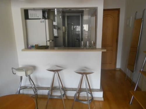 Área de bar da cozinha moderna com três banquetas no Hostel New Ipanema, Rio de Janeiro, com eletrodomésticos em aço inoxidável