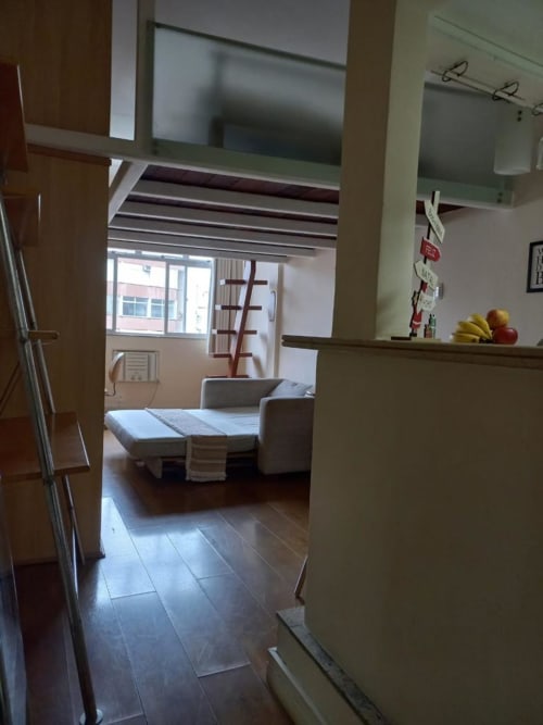 Área aberta de cozinha-sala no Hostel New Ipanema, Rio de Janeiro, com sofá-cama, janelas e vista da cidade