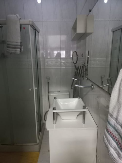 Banheiro moderno na Pousada New Ipanema Rio de Janeiro com pia branca, box de vidro e design minimalista limpo