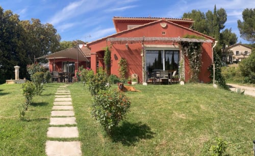 Gîte Domaine des Lavarines à Morières-lès-Avignon, bâtiments en terre cuite rouge, pelouse verdoyante et allée pavée