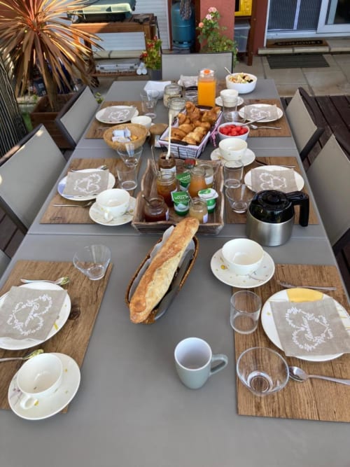 Table du petit-déjeuner au Domaine des Lavarines avec viennoiseries, fruits frais, café et couverts