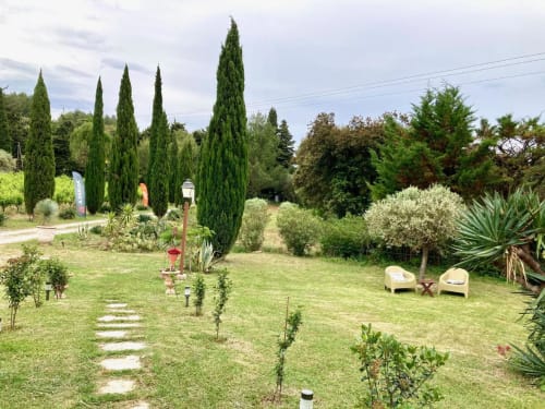 Lush garden at Domaine des Lavarines B&B in Morières-lès-Avignon with cypress trees, loungers, and winding paths