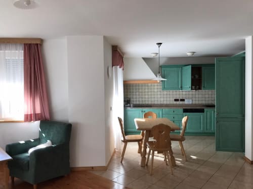 Greppa Apartment im Residence Rodolon in Mazzin mit türkisfarbener Küche, Essbereich und Wohnzimmer mit Bergblick