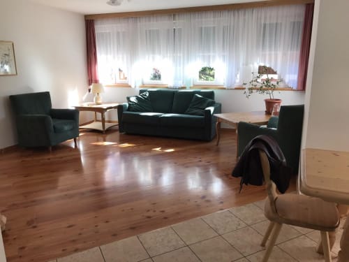 Spacious living area of Greppa Apartment at Residence Rodolon with black furniture, wooden floors, and mountain views from