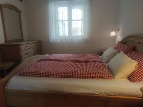 Cozy bedroom in Greppa Apartment at Residence Rodolon, Mazzin, with red checkered bedding, wooden furniture, and mountain