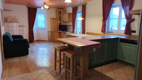 Dona-Apartment im Residence Rodolon in Mazzin mit offener Küche, Essbereich mit Holztisch und Wohnzimmer mit