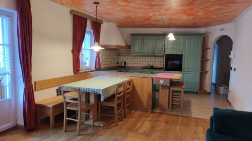 Spacious kitchen and dining area in Dona Apartment at Residence Rodolon, Mazzin, with wooden furnishings and green cabinetry