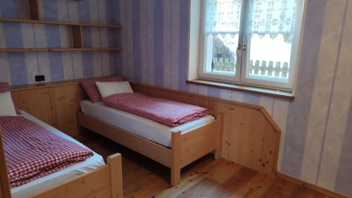 Twin bedroom in Dona Apartment at Residence Rodolon, Mazzin, with wooden beds, red checkered bedding, and garden view windows