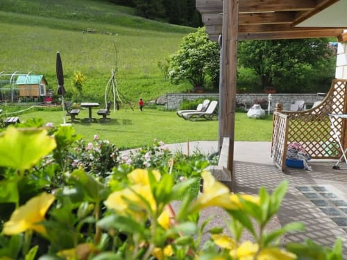 Lush garden view from Dona Apartment at Residence Rodolon in Mazzin, with terrace, seating, and green lawn