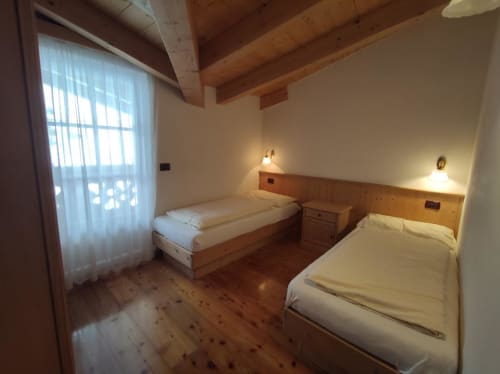 Twin bedroom in Sass Becè Apartment at Residence Rodolon, Mazzin, with wooden beams and mountain views