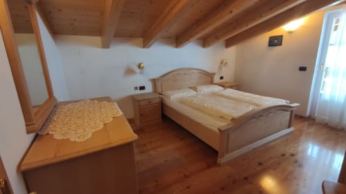 Cozy mountain apartment bedroom at Residence Rodolon with wooden beams, twin beds, and traditional Alpine furnishings in