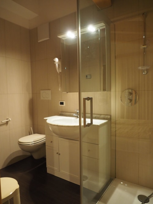 Modern bathroom at Residence Rodolon Sassolungo Apartment in Mazzin with glass shower, white vanity, and toilet