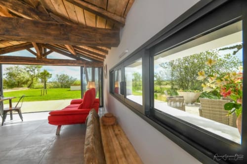 Salon moderne à la Gîtes De La Grande Borderie avec fauteuil rouge, poutres en bois et vue sur la campagne française