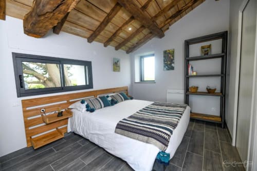 Chambre moderne aux Gîtes de la Grande Borderie à Saint-Gervais : lit en bois, poutres apparentes et carrelage foncé