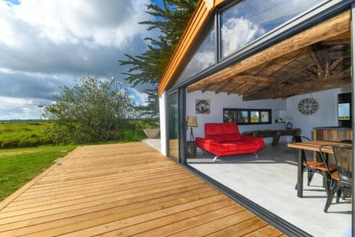 Villa contemporaine aux Gîtes de La Grande Borderie avec terrasse en bois, sièges rouges et vues panoramiques sur la campagne