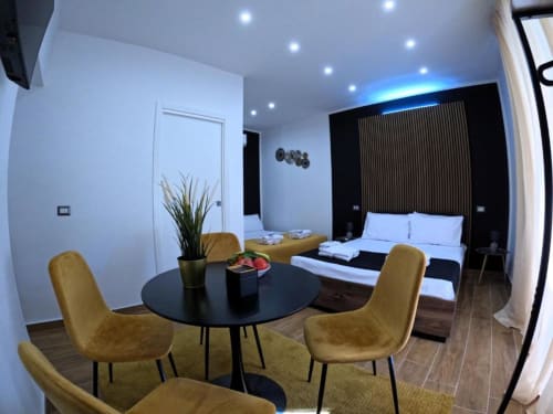 Camera moderna dell'hotel Blackwoody a Napoli con sedie gialle, letto nero e arredi contemporanei
