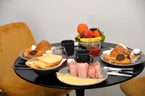 Colazione abbondante al Blackwoody BCH Tribunali con cornetti, formaggi, salumi, frutta, succo e caffè su tavolo nero