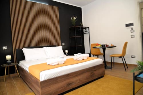 Camera Doppia Superiore Moderna presso Blackwoody Contemporary Hospitality a Napoli con letto in legno, accenti arancioni, zona pranzo
