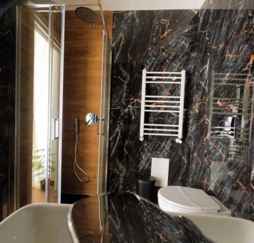 Bagno moderno con pareti in marmo nero, water bianco, scaldasalviette, cabina doccia walk-in e finiture eleganti presso Blackwoody
