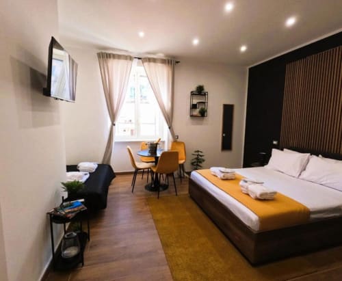 Camera moderna presso Blackwoody Contemporary Hospitality a Napoli con letto queen, accenti gialli, scrivania, TV e vista città