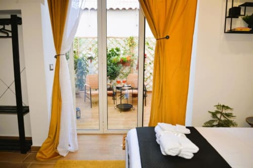 Luminosa camera matrimoniale con terrazza vista giardino presso il Blackwoody B&B a Napoli, con tende gialle e arredi moderni