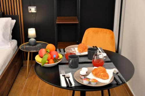 Setup colazione moderna in camera d'hotel con cornetti, frutta fresca e succo presso Blackwoody Contemporary Hospitality a Napoli