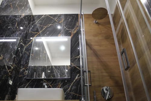 Bagno moderno presso il Blackwoody Contemporary Hospitality di Napoli. Pareti in marmo nero con venature dorate, specchio illuminato