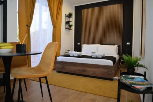 Camera moderna presso Blackwoody Contemporary Hospitality a Napoli con letto in legno, tende dorate e arredi contemporanei
