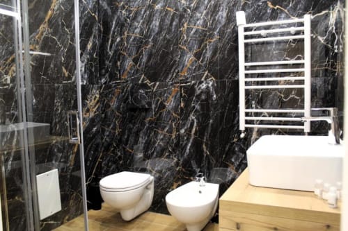 Bagno moderno a Blackwoody Contemporary a Napoli con marmo nero venato, sanitari bianchi, scaldasalviette e bidet
