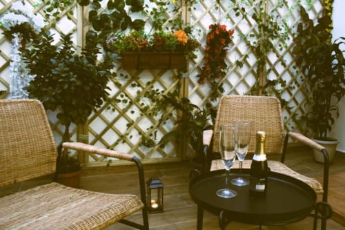 Sedie in vimini e tavolo rotondo sulla terrazza del giardino con pannello in traliccio e cesti di fiori sospesi al Blackwoody Contemporary