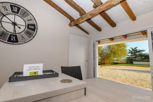 Espace bureau de villa moderne aux Gites De La Grande Borderie avec bureau, horloge en chiffres romains, poutres en bois apparent et jardin