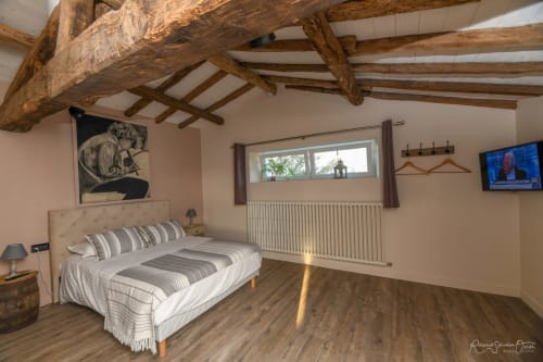 Spacieuse chambre de villa aux Gites De La Grande Borderie avec poutres en bois apparentes, literie rayée et équipements modernes