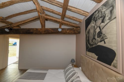 Chambre de villa moderne aux poutres en bois apparentes, murs blancs, œuvres d'art et lit confortable aux Gites De La Grande Borderie
