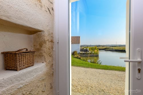 Porte ouverte du Gîte De La Grande Borderie révélant une villa riveraine à Saint Gervais avec intérieur en pierre et vue panoramique sur l'eau
