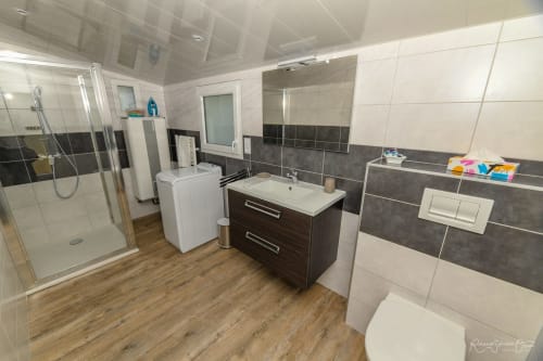 Salle de bain moderne aux accents de carrelage foncé, vasque, douche et boiseries à la villa Gîtes De La Grande Borderie à Saint-Gervais