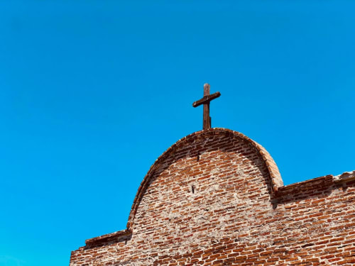 Croce in legno sulla cupola in laterizio della storica chiesa di Bari, Italia, con cielo azzurro limpido