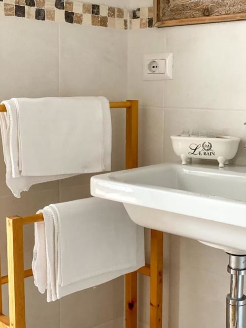 Bagno di SoleMagia a Vernazzo con asciugamani bianchi su portasciugamani in legno e lavabo a colonna