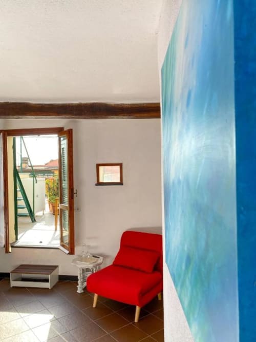Luminosa camera della SoleMagia B&B a Vernazzo con sedia rossa, parete azzurra, travi in legno e accesso alla terrazza