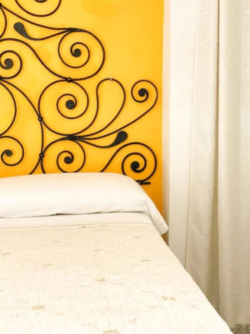 Camera da letto SoleMagia a Vernazzo con testiera giallo brillante decorata con motivi neri e biancheria bianca